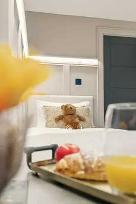 a teddy bear sitting on a bed with a tray of food at 2BR West End Apartment Near Botanic Gardens in Glasgow