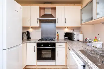 a kitchen with white cabinets and a stove top oven at 4 Bedroom Townhouse In Stirling in Stirling