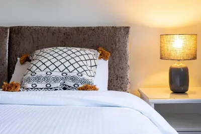 a bedroom with a bed with a pillow and a lamp at 4 Bedroom Townhouse In Stirling in Stirling