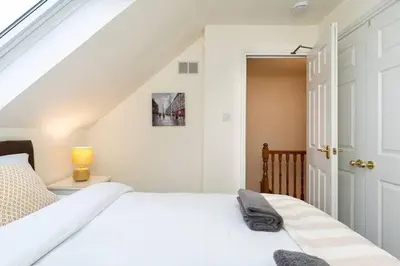 a white bedroom with a white bed and a door at 4 Bedroom Townhouse In Stirling in Stirling