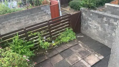 a wooden fence with plants next to a sidewalk at OakHouse- Entire 3 Bedroom Terrace House with Free Parking in Cumbernauld