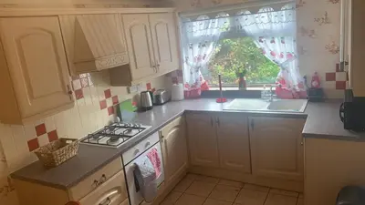 a kitchen with a stove and a sink and a window at OakHouse- Entire 3 Bedroom Terrace House with Free Parking in Cumbernauld