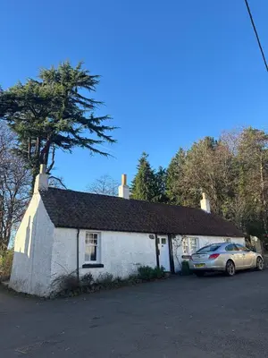 a white house with a car parked in front of it at Ivy Cottage in Causewayhead