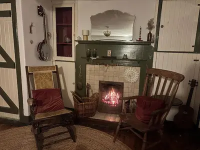 a living room with a fireplace and two chairs at Ivy Cottage in Causewayhead