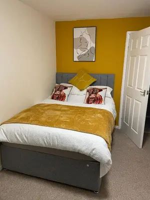 a bedroom with a large bed with yellow walls at Spacious two bedroom flat, entire property in Greenock