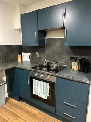 a kitchen with blue cabinets and a stove with pots and pans at Edinburgh Rose Suites 1BHK Central EB4 in Edinburgh