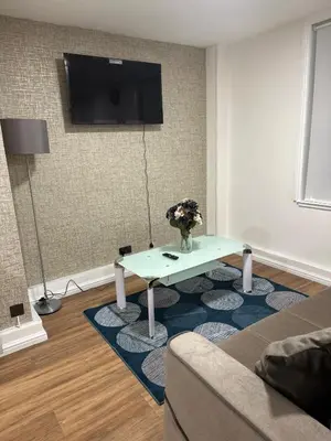 a living room with a table and a tv on a wall at Edinburgh Rose Suites 1BHK Central EB4 in Edinburgh