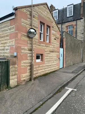a brick building with a mirror on the side of it at Coorie Cottage in Edinburgh