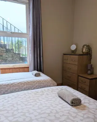 a bedroom with two beds and a window at Kintyre apartment in Campbeltown