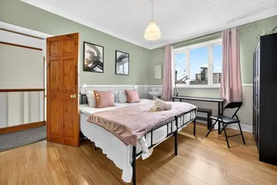 a bedroom with a bed with pink pillows and a desk at Spacious 5BR Home in Cardiff Bay with Office Area in Moffat