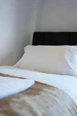 two beds with white sheets and a black headboard at Caldwell House in Glasgow