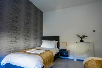 a bedroom with two beds and a brick wall at Caldwell House in Glasgow