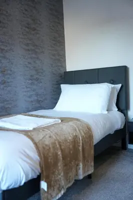 a bed with white sheets and a brown blanket on it at Caldwell House in Glasgow