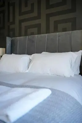 a bed with white sheets and pillows in a room at Caldwell House in Glasgow