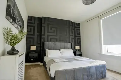 a bedroom with a large bed and a large window at Caldwell House in Glasgow
