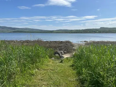 a path through the grass next to a body of water at Dunmore Cottage in Tarbert