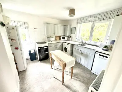 a kitchen with white cabinets and a table in it at Dunmore Cottage in Tarbert