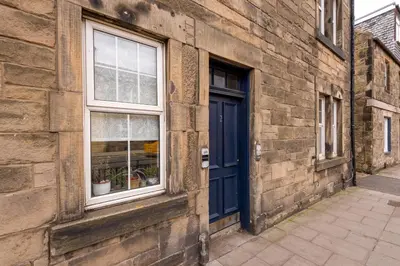 a brick building with a blue door and a window at Andy's Pad in Edinburgh