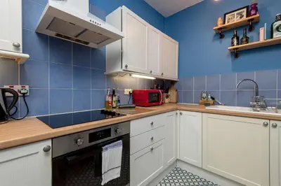 a kitchen with white cabinets and a blue wall at Andy's Pad in Edinburgh