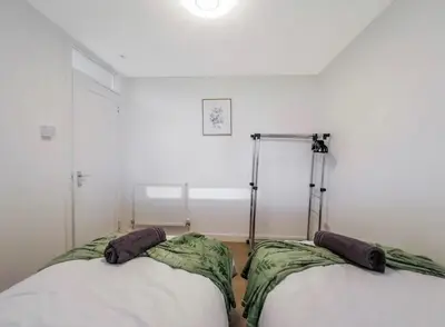two beds in a room with white walls at Free Parking - 3 Bedrooms - Sleeps 7 - Airport in Paisley