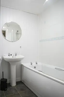 a white bathroom with a sink and a tub and a mirror at Neilston Gateaway in Paisley