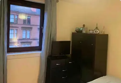 a bedroom with a window and a dresser and a dresser with a television at City Centre Double Room in Glasgow