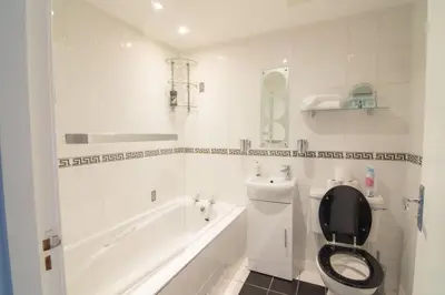 a white bathroom with a toilet and a bath tub at Central Renfrew 1BR Apt in Renfrew