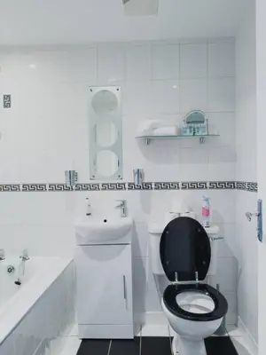 a white bathroom with a black toilet and a sink at Central Renfrew 1BR Apt in Renfrew