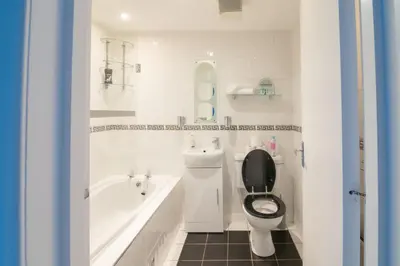 a bathroom with a toilet and a tub and a sink at Central Renfrew 1BR Apt in Renfrew