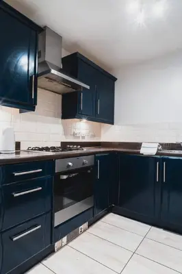 a kitchen with dark blue cabinets and a stove at Modern 2-Bed Near Braehead in Renfrew