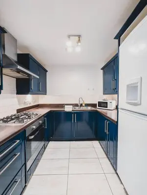 a kitchen with blue cabinets and a white appliances at Modern 2-Bed Near Braehead in Renfrew