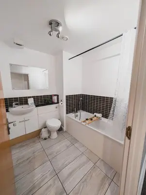 a bathroom with a toilet and a tub and a sink at Modern 2-Bed Near Braehead in Renfrew