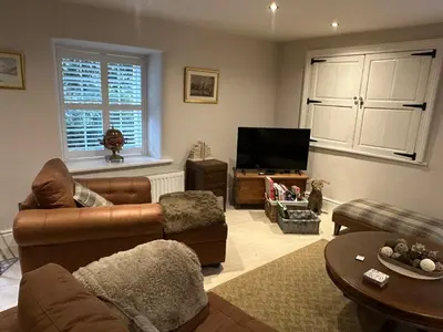 a living room with a couch and a television at The Oldest House Located in the heart of Matlock in Moffat