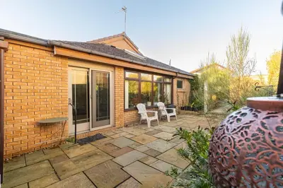 a patio with two white chairs and a house at Bright, spacious house in Edinburgh