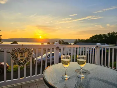 two glasses of wine on a table on a balcony with the sunset at Wemyss Bay Seaview Sanctuary in Wemyss Bay