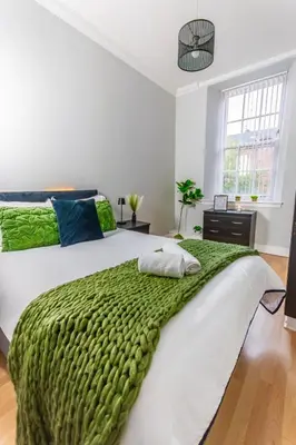 a bedroom with a green blanket on a bed at FREE Pool Table Cinema Room TableTennis AirHockey Glasgow City in Glasgow