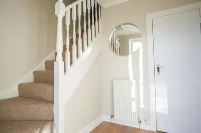 a hallway with stairs with a mirror and a stairway at Castlehill House in Boʼness