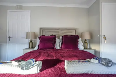 a bedroom with a large bed with purple blankets and pillows at Castlehill House in Boʼness