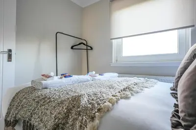 a white room with a bed with a window at Castlehill House in Boʼness