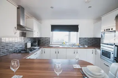 a kitchen with a wooden table and two wine glasses at Modern 3BR Flat with Parking in Renfrew