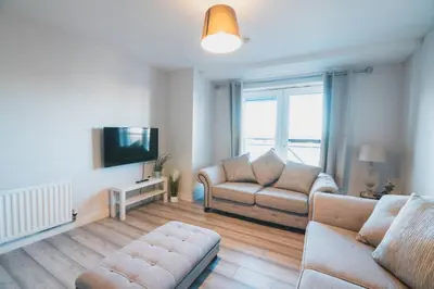 a living room with a couch and a tv at Top-Floor 2-Bed Near Braehead in Renfrew