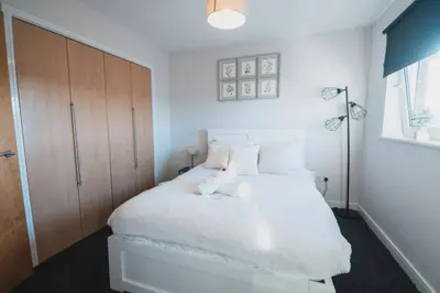 a bedroom with a white bed with white sheets and pillows at Top-Floor 2-Bed Near Braehead in Renfrew