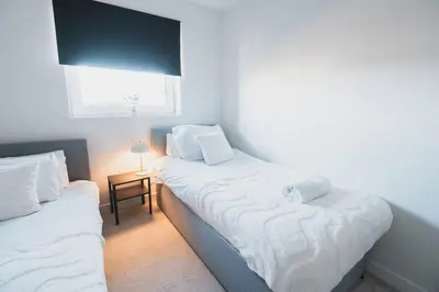 a bedroom with two beds with white sheets and a window at Top-Floor 2-Bed Near Braehead in Renfrew