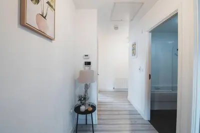 a hallway with a floor lamp and a bathroom at Top-Floor 2-Bed Near Braehead in Renfrew