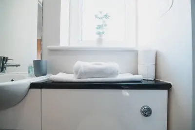a bathroom with a sink and a towel on a counter at Top-Floor 2-Bed Near Braehead in Renfrew