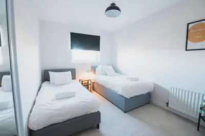 a room with two beds and a table with a lamp at Top-Floor 2-Bed Near Braehead in Renfrew