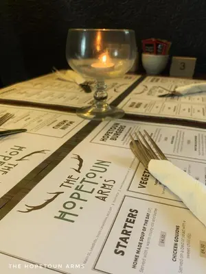 a table with a menu and a candle on it at The Hopetoun Arms Hotel in Leadhills