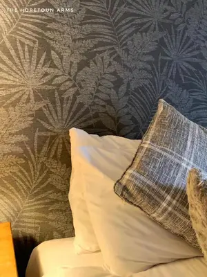 a bedroom with a pillow and a wall with a plant wallpaper at The Hopetoun Arms Hotel in Leadhills
