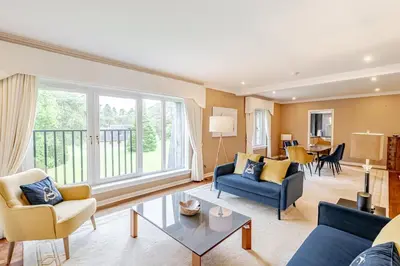 a living room with blue furniture and a large window at Spacious Gleneagles Apartment