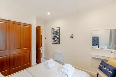 a white room with a bed and a wooden door at Spacious Gleneagles Apartment